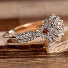 a close up of a diamond ring on top of a wooden table with other jewelry items