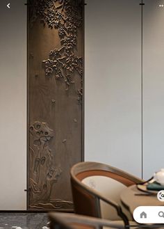 a room divider with an intricate design on the wall and chairs in front of it