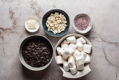 bowls filled with marshmallows, chocolate chips and sprinkles