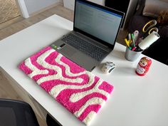 a laptop computer sitting on top of a desk next to a pink and white rug