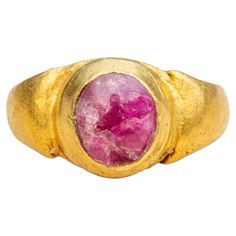 A scarce early Javanese gold and ruby ring dating from the 7th-15th century Indonesian Classical period. As expected with Javanese gem-set gold rings made in this period, the present ring is crafted high-karat gold and set with a polished cabochon. The ring has a circular bezel, holding a ruby of approximately 0.7cts. The ruby is of a pinkish red colour and features natural inclusions throughout. The protuberant, stirrup-shaped shoulders of the ring are designed to mimic the shape of water buffa Antique Gold Ruby Ring With Bezel Setting, Antique Ruby Cabochon Ring, Gold Byzantine Ruby Ring, Gold Byzantine Style Ruby Ring, Gold Byzantine Ruby Ring With Gemstone, Antique Ruby Ring For Ceremonial Occasions, Spiritual Gold Ruby Rings, Spiritual Gold Rings With Ruby, Spiritual Oval Ruby Ring