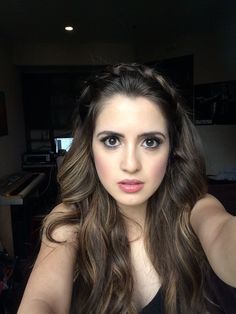 a woman with long hair taking a selfie in the mirror while wearing a black top