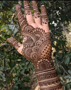 a hand with henna on it and trees in the background