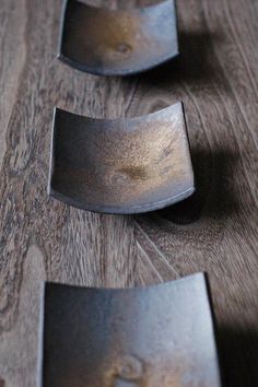 three pieces of metal sitting on top of a wooden table