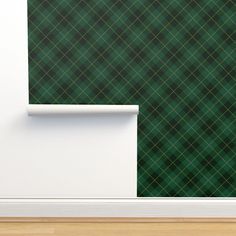 a green and black plaid wallpaper next to a white door with a wooden floor