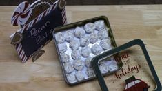 two tins filled with snowballs sitting on top of a wooden table next to each other