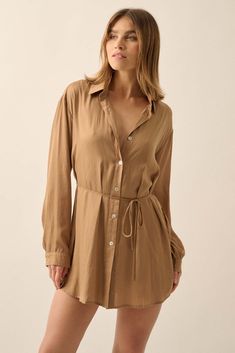 Matte-finish satin romper. Layered design with dress shirt overlayer and shorts lining. Collared neckline. Button-front closure with pearly shell buttons. Long sleeves with buttoned cuffs. Drop shoulder. Removable tie belt. Side slits. Yoke back. Curved shirttail hem. Thigh length. Relaxed fit. 100% Polyester. Imported. Designed in LA. Model wears size S. Chic Solid Mini Dress With Button Closure, Summer Shirt Dress With Button Closure For Date Night, Summer Shirt Dress For Date Night With Button Closure, Summer Date Night Shirt Dress With Button Closure, Summer Button-up Shirt Dress For Date Night, Elegant Rayon Shirt Dress For Summer, Chic Rayon Shirt Dress For Daywear, Chic Long Sleeve Rayon Mini Dress, Formal Summer Button-up Shirt Dress