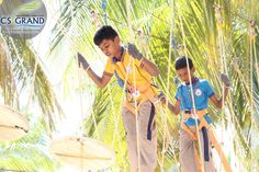 two young boys standing on ropes in front of palm trees