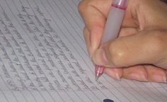 a person writing on lined paper with a pen