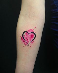 a small heart tattoo on the left inner arm, with watercolor splatters