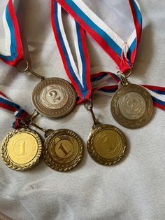 four medals with ribbons around them sitting on a bed