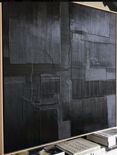 a large black painting sitting on top of a wooden shelf