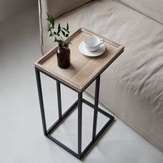 a small table with a cup and saucer on it next to a beige couch