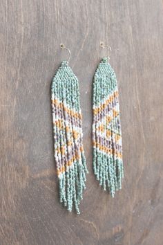 two pairs of beaded earrings sitting on top of a wooden table