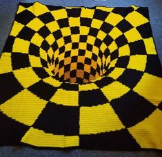 a black and yellow knitted blanket with an image of the center in the middle