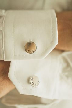 a close up of a person wearing a white shirt with a gold button on it