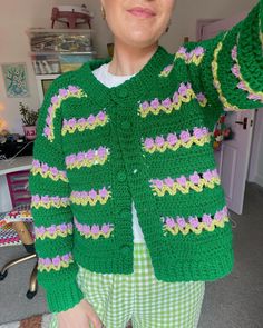 a woman is wearing a green crocheted sweater