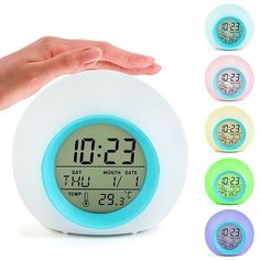 an alarm clock with five different colors in front of it and hand holding the clock