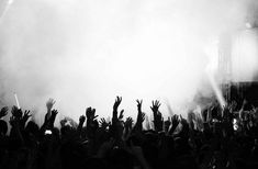 a group of people that are standing in front of a stage with their hands up