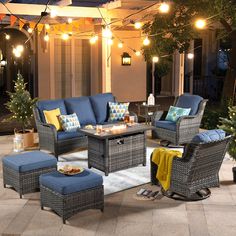 an outdoor living room with blue furniture and christmas lights on the ceiling, surrounded by potted trees