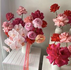 two white vases with pink and red flowers in them