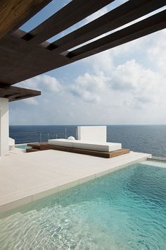 an outdoor swimming pool with the ocean in the backgroung and sky above it