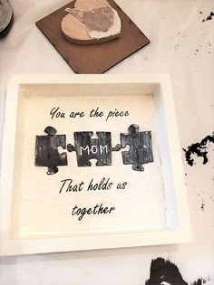 a piece of puzzle sitting on top of a white table next to a heart shaped rock