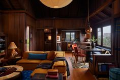 a living room filled with furniture and lots of wood paneling on the walls next to windows