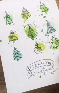 someone is drawing christmas trees on a piece of paper with watercolors and ink