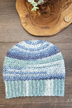 a blue and white knitted hat sitting on top of a wooden table next to a plant