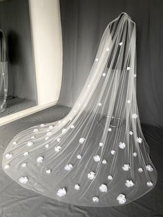 a veil with white flowers on it sitting in front of a mirror