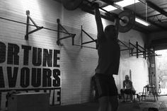 a man is lifting a barbell in a crossfit gym with other people