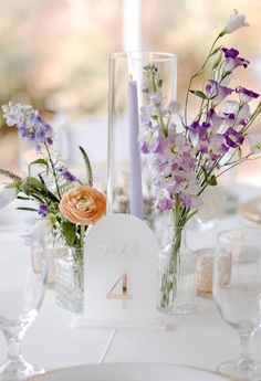 the table is set with flowers in vases and place cards on top of each other