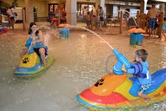 two children on bumper boats playing in the water at an indoor pool and splash park