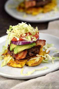 a white plate topped with a burger covered in lettuce and tomato