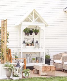 a white shed with potted plants and other things on it's shelves in the back yard