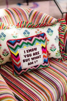 a colorful bed with two pillows and a pillow that says i know you are but what am i?