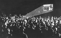 an old black and white photo with the words at the movies above it is a large group of people