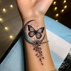 a woman's arm with a butterfly on the moon and stars tattoo design in black ink