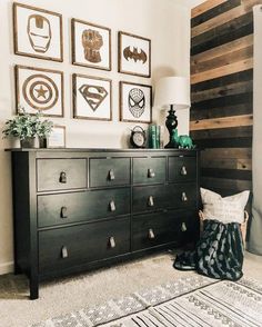 a black dresser sitting next to a wall with pictures on it