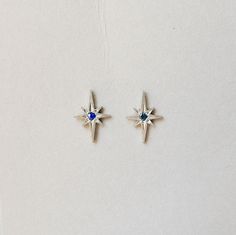 These earrings are a silver version of the beautiful 14k rose gold Polaris Earrings. This sterling silver earring is paired with a blue sapphire center stone which gives it a beautiful antique vibe. Details: Sterling silver stud measures about 11.16 x 7.8mm Blue Sapphires measure about 1.6mmSOLD AS A PAIR Free Shipping on Domestic Orders Materials: sterling silver, sapphire, blue sapphire Sterling Silver Sapphire Gemstone Earrings, Sterling Silver Celestial Earrings For Gift, Silver Sapphire Earrings With Gemstones, Sapphire Earrings As A Gift, White Gold Sterling Silver Birthstone Earrings, Pierced Sapphire Earrings As Gift, Celestial White Gold Sterling Silver Earrings, White Gold Sterling Silver Gemstone Earrings, Celestial Sapphire Sterling Silver Jewelry