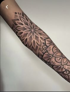 a person with a tattoo on their arm that has an intricate flower design in the middle