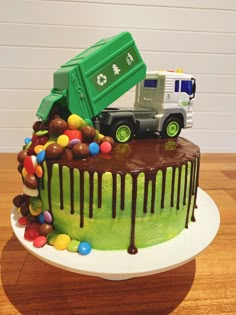 a birthday cake with a garbage truck on top and candy balls all around the cake