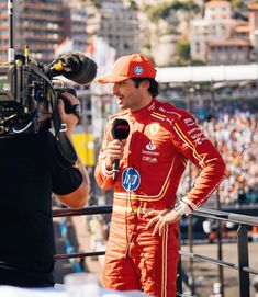 a man in an orange race suit talking to someone