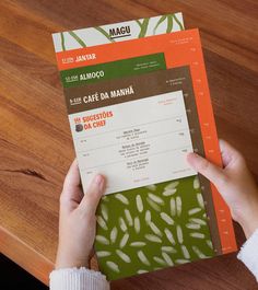 a person holding up a menu on top of a wooden table