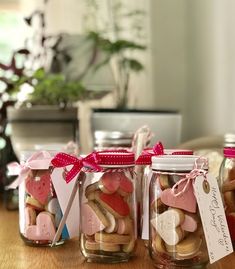 three jars filled with heart shaped cookies on top of a table