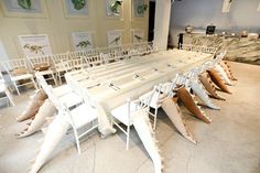 there are many chairs and tables in the room with white tablecloths on them