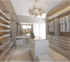 a walk in closet with lots of white clothes on shelves and hanging lights above it