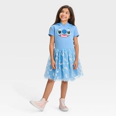 This Lilo & Stitch Hooded Cosplay Dress will grab your child's attention instantly with its out-of-this-world style. Designed in a pretty shade of light blue, the pullover dress features a short-sleeve bodice with a cute illustration of their fave blue alien, and an attached hood with his 3D ears. The flouncy knee-length mesh skirt is adorned with an allover silver silhouetted print of Stitch's face for additional shine and style. Made with soft, stretchy scuba fabric, the cosplay dress offers f Blue Alien, Shades Of Light Blue, Scuba Fabric, Scuba Dress, Lilo Stitch, Mesh Skirt, Cosplay Dress, Lilo And Stitch, Birthday Outfit