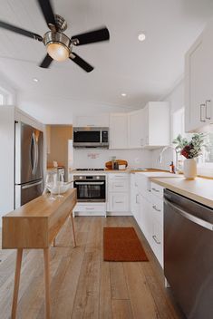 a kitchen with white cabinets and stainless steel appliances, including a ceiling fan in the center